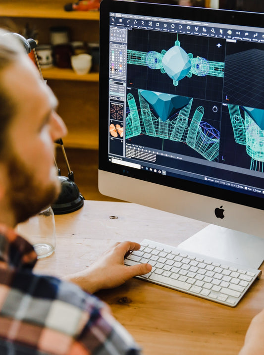 W.R. Metalarts founder Will looking at a Apple computer screen of some rendered 3 dimensional image ring designs